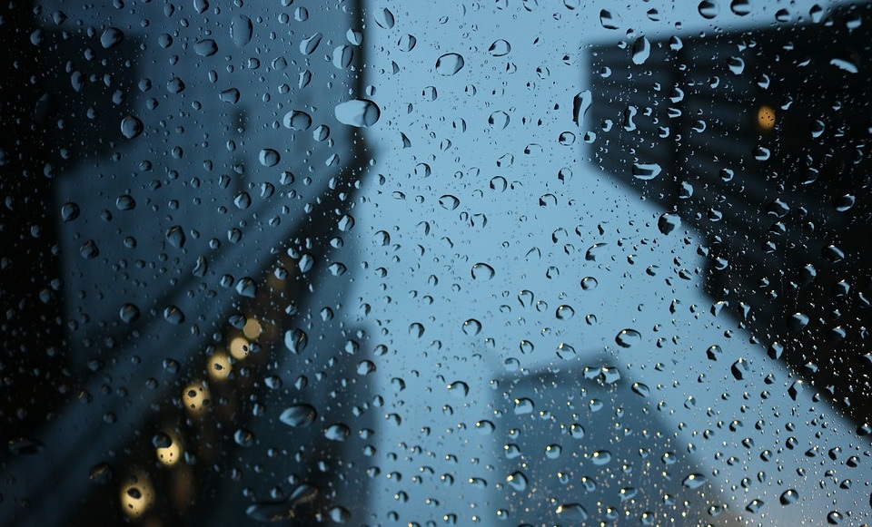 Rain droplets on camera lens over cityscape