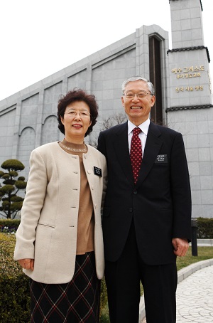 A senior missionary couple standing in front of a Temple