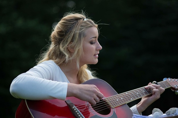 Young woman playing an original tune on her guitar